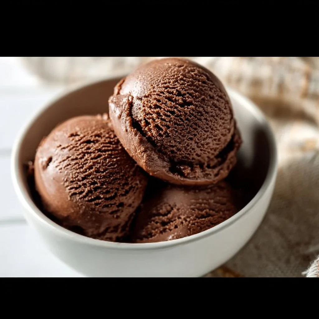Bowl of creamy chocolate cottage cheese ice cream topped with cocoa nibs.